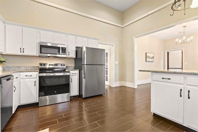 kitchen featuring stainless steel appliances, white cabinetry, and light stone counters