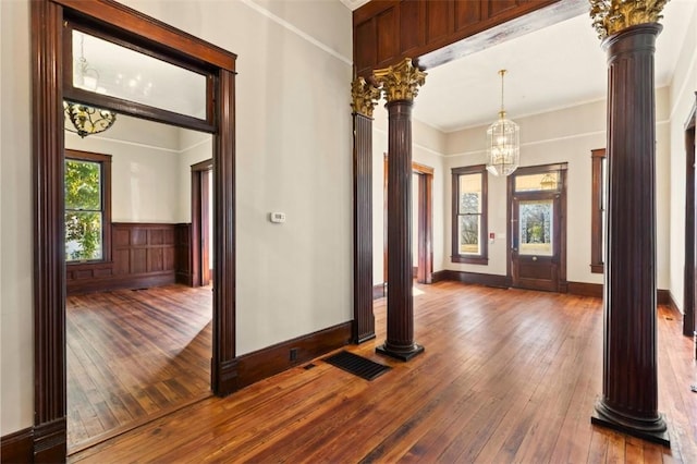 entrance foyer with ornamental molding, decorative columns, and hardwood / wood-style floors