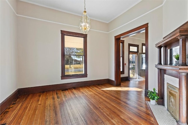 unfurnished dining area featuring a notable chandelier, wood-type flooring, and ornamental molding