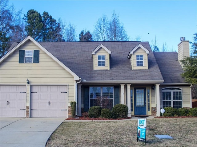 new england style home featuring a garage, concrete driveway, and a front yard