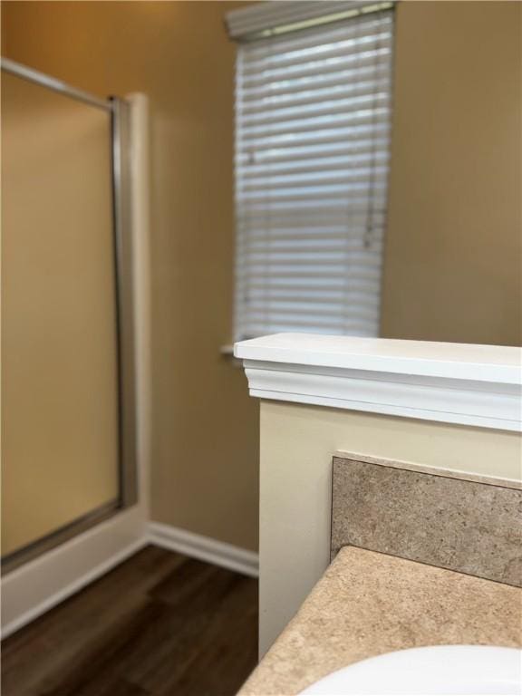 bathroom with a shower stall, baseboards, and wood finished floors