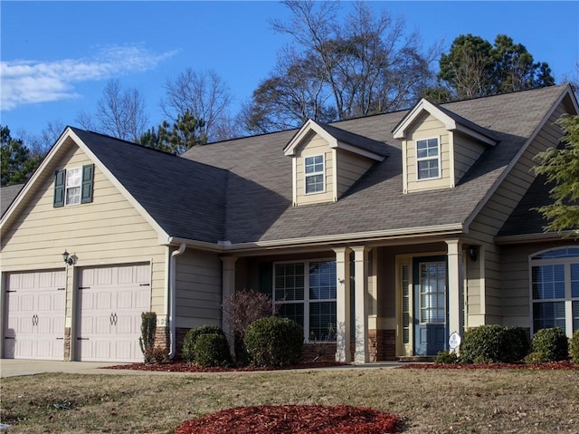 cape cod-style house with a garage, driveway, stone siding, and a front yard