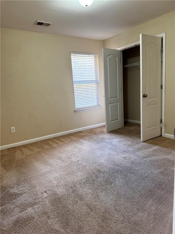 unfurnished bedroom featuring a closet, carpet, visible vents, and baseboards