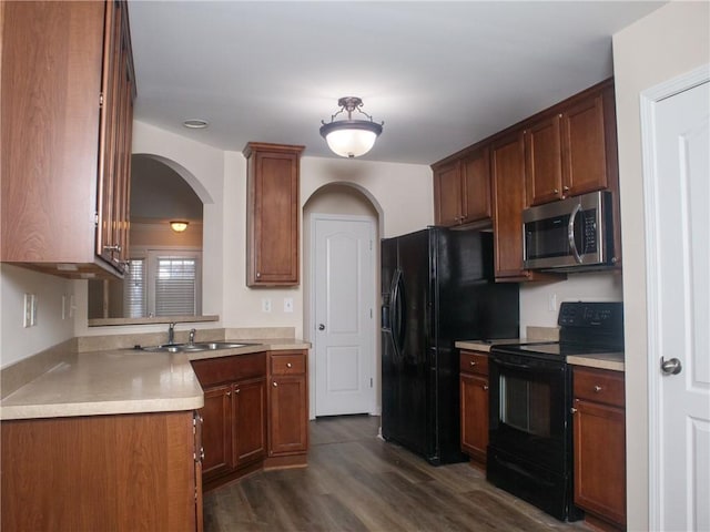 kitchen with arched walkways, dark wood-style flooring, a sink, light countertops, and black appliances