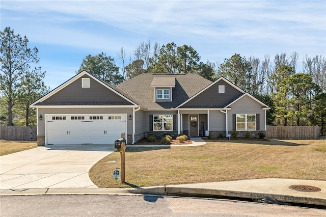 craftsman-style home featuring concrete driveway, an attached garage, a front yard, fence, and stone siding