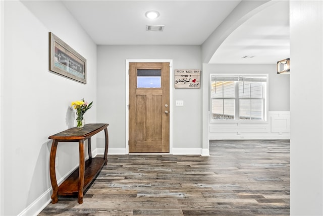 foyer with plenty of natural light, visible vents, arched walkways, and wood finished floors