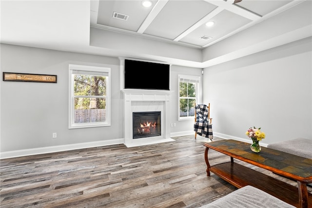 living area with visible vents, a fireplace with flush hearth, wood finished floors, coffered ceiling, and baseboards