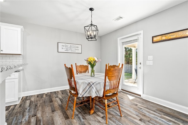 dining space featuring an inviting chandelier, visible vents, baseboards, and wood finished floors