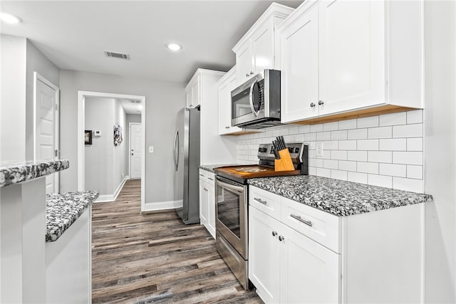 kitchen featuring stainless steel appliances, dark wood-type flooring, visible vents, white cabinets, and decorative backsplash