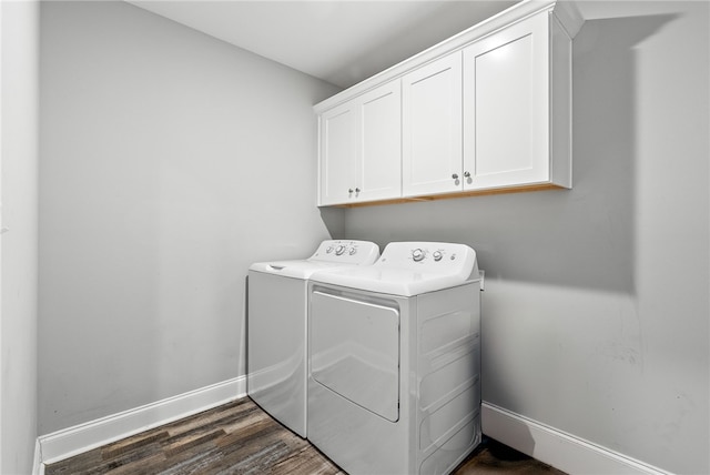 clothes washing area with washing machine and dryer, cabinet space, dark wood finished floors, and baseboards