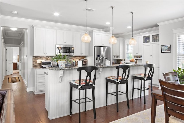 3412 Double Eagle Ln, Opelika, AL 36801 - kitchen featuring appliances with stainless steel finishes, a kitchen island with sink, backsplash, white cabinetry, and dark wood-type flooring