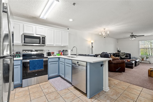 kitchen with sink, light carpet, appliances with stainless steel finishes, kitchen peninsula, and white cabinets