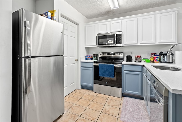 kitchen featuring sink, white cabinetry, a textured ceiling, light tile patterned floors, and appliances with stainless steel finishes