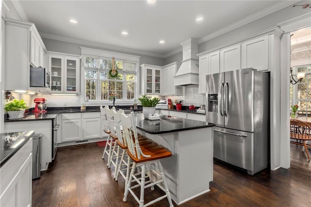 kitchen featuring white cabinetry, custom exhaust hood, stainless steel appliances, backsplash, and a kitchen island