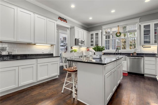 kitchen with white cabinets, appliances with stainless steel finishes, dark hardwood / wood-style flooring, and a center island