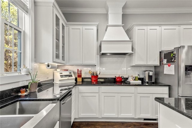 kitchen featuring dark stone countertops, decorative backsplash, crown molding, white cabinetry, and appliances with stainless steel finishes