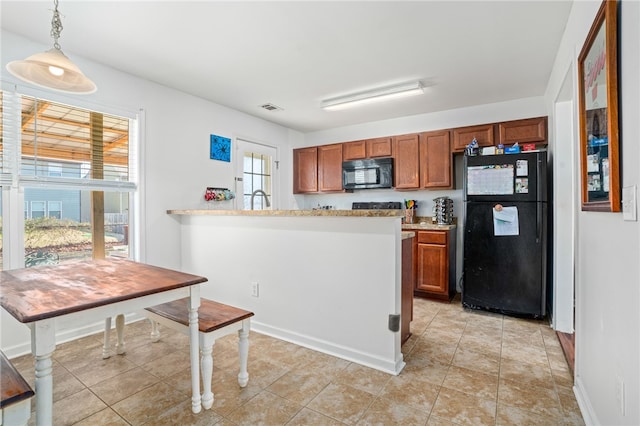 kitchen with light tile patterned floors, hanging light fixtures, and black appliances