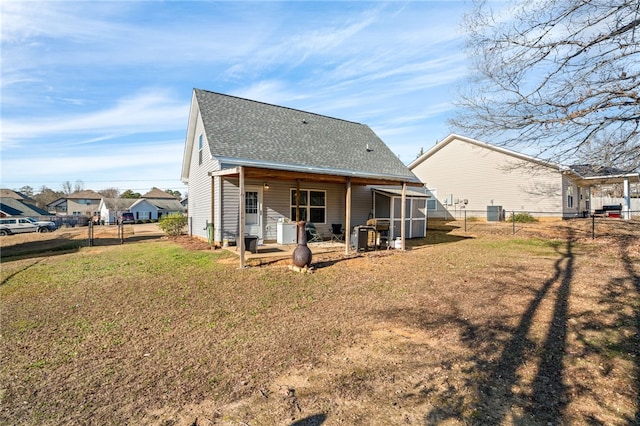 rear view of property featuring a lawn and cooling unit