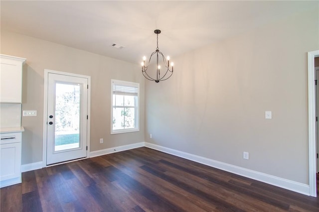 unfurnished dining area with dark hardwood / wood-style flooring and an inviting chandelier