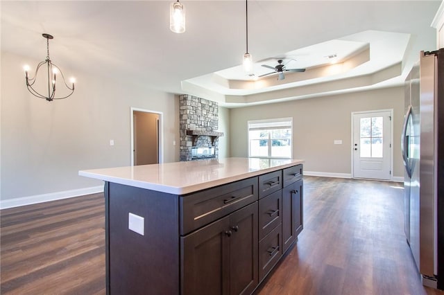 kitchen featuring a raised ceiling, a center island, dark hardwood / wood-style floors, stainless steel refrigerator, and hanging light fixtures