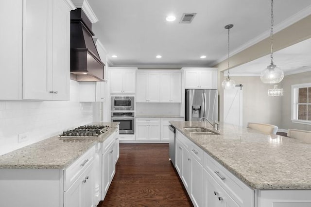 kitchen with an island with sink, sink, white cabinets, stainless steel appliances, and custom range hood