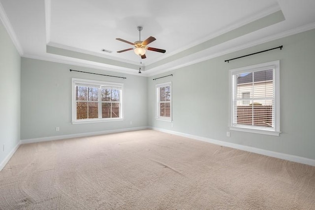 carpeted spare room featuring ornamental molding, a raised ceiling, and a wealth of natural light