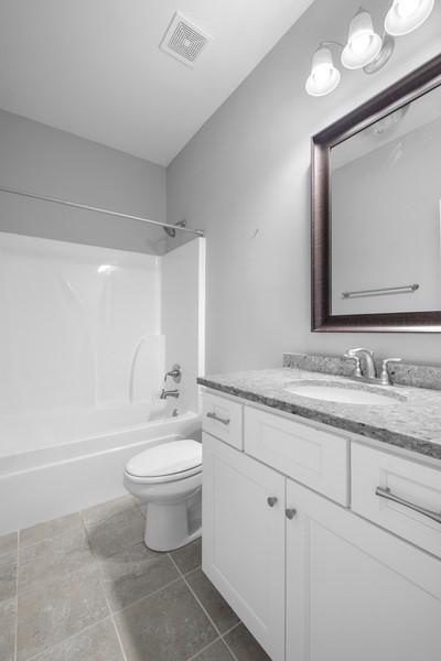 full bathroom with vanity, tile patterned floors, toilet, and washtub / shower combination