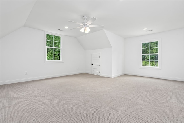 additional living space with light colored carpet, plenty of natural light, ceiling fan, and lofted ceiling