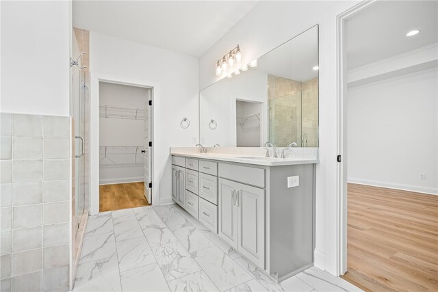 bedroom with ensuite bathroom, ceiling fan, a raised ceiling, and light wood-type flooring