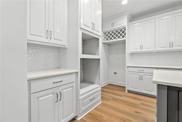 kitchen featuring white cabinets, light wood-type flooring, and tasteful backsplash