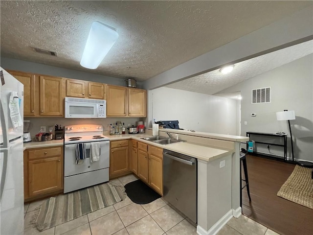 1385 S Donahue Dr Unit 4201, Auburn, AL 36832 - kitchen featuring white appliances, a peninsula, a textured ceiling, light countertops, and a sink