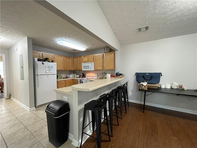 1385 S Donahue Dr Unit 4201, Auburn, AL 36832 - kitchen featuring white appliances, a textured ceiling, a peninsula, baseboards, and a breakfast bar