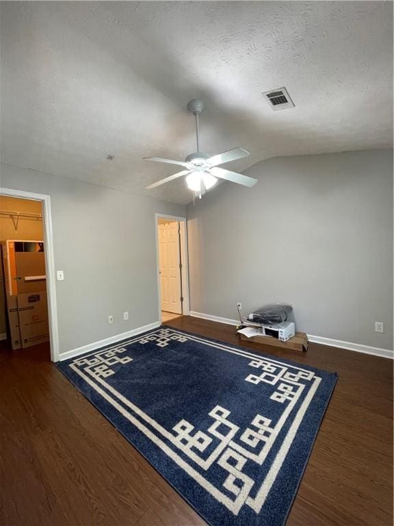 1385 S Donahue Dr Unit 4201, Auburn, AL 36832 - unfurnished room with baseboards, ceiling fan, dark wood-style flooring, vaulted ceiling, and a textured ceiling