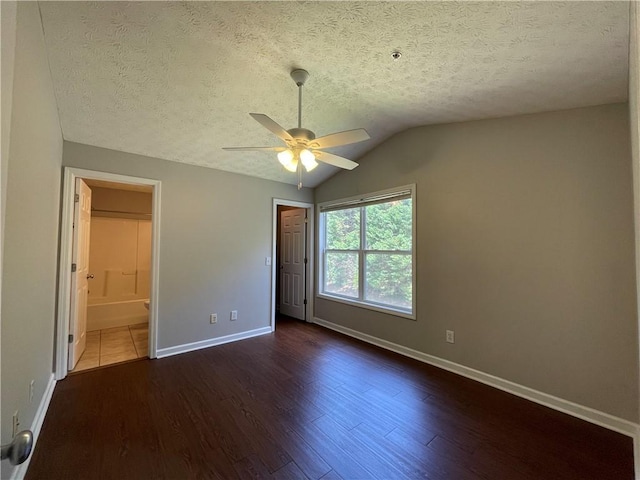 1385 S Donahue Dr Unit 4201, Auburn, AL 36832 - unfurnished bedroom featuring baseboards, dark wood finished floors, a textured ceiling, lofted ceiling, and ensuite bath