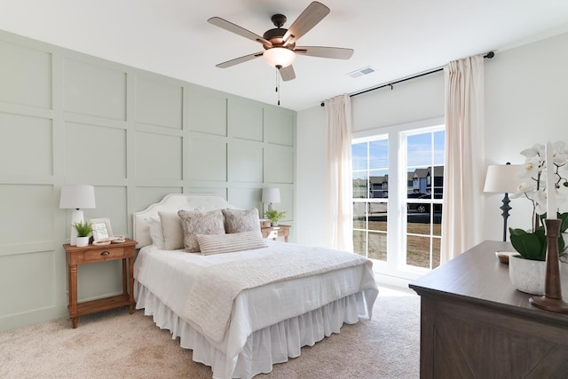 bedroom featuring ceiling fan, light carpet, a decorative wall, and visible vents