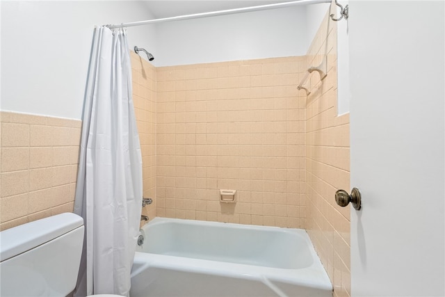 full bathroom with wainscoting, toilet, tile walls, and shower / bathtub combination with curtain