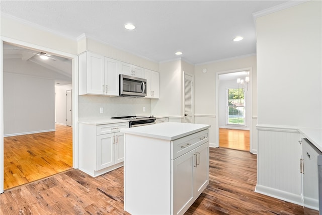 kitchen featuring crown molding, stainless steel appliances, light wood finished floors, light countertops, and white cabinetry