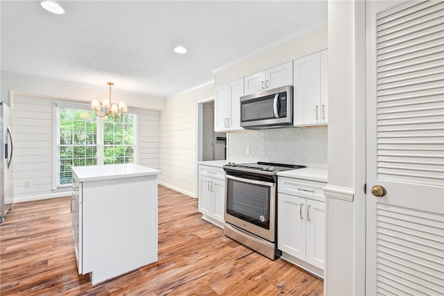 kitchen featuring stainless steel appliances, light countertops, ornamental molding, a kitchen island, and a notable chandelier