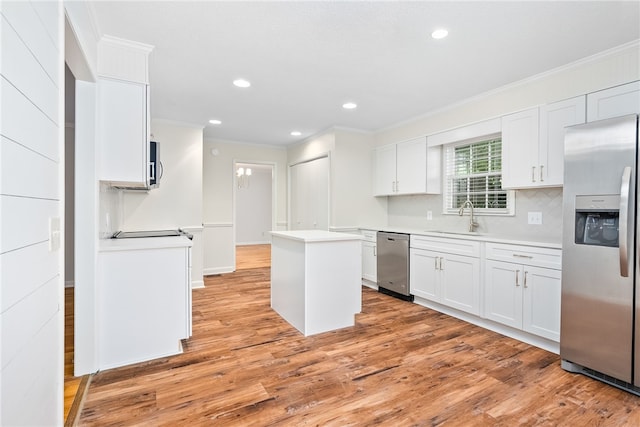 kitchen with ornamental molding, appliances with stainless steel finishes, a sink, and a kitchen island