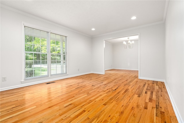 spare room with light wood-style flooring, visible vents, crown molding, and a notable chandelier