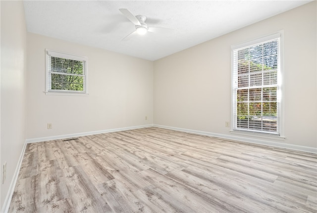 spare room featuring light wood-style flooring, a wealth of natural light, and baseboards