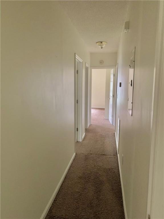 hall with a textured ceiling and light colored carpet