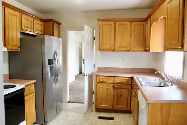 kitchen with white dishwasher, range with electric cooktop, a sink, light countertops, and brown cabinetry