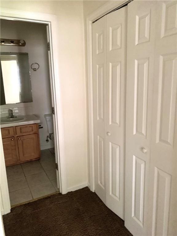 corridor featuring dark colored carpet and sink