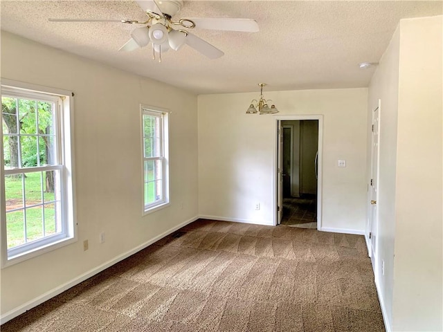 spare room featuring carpet, a textured ceiling, and ceiling fan with notable chandelier