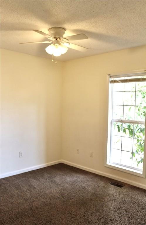 spare room with visible vents, dark carpet, and a textured ceiling