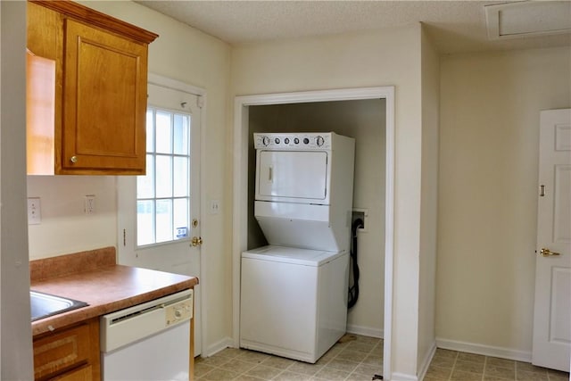 clothes washing area featuring stacked washer / dryer, laundry area, a textured ceiling, and baseboards