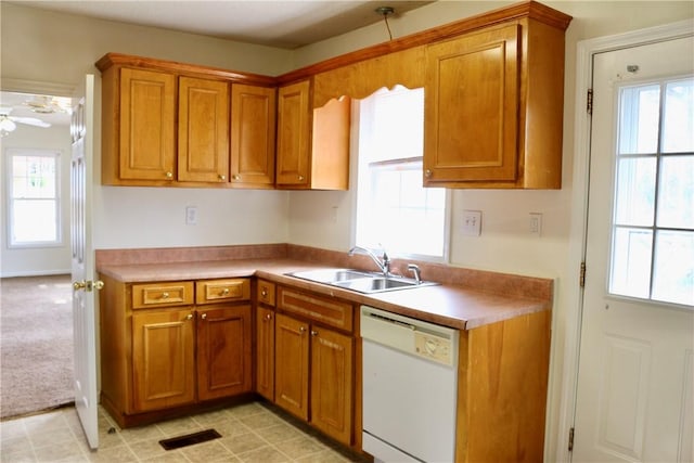 kitchen with a healthy amount of sunlight, white dishwasher, brown cabinets, and a sink