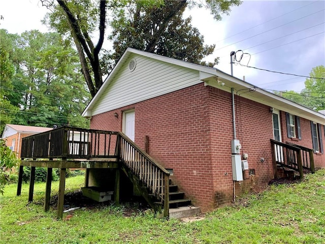 view of side of property featuring a yard, brick siding, stairway, and a wooden deck