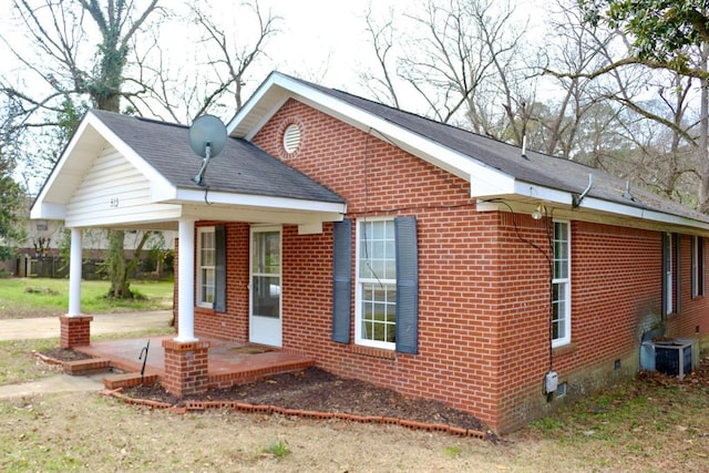 exterior space featuring brick siding, a shingled roof, covered porch, crawl space, and cooling unit